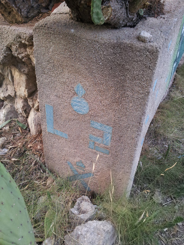 Perduda en la vegetació trobem la pilona amb la seva denominació.